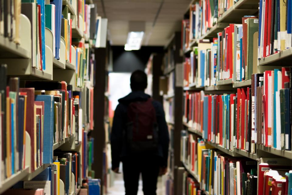 Person Walking between shelves in library