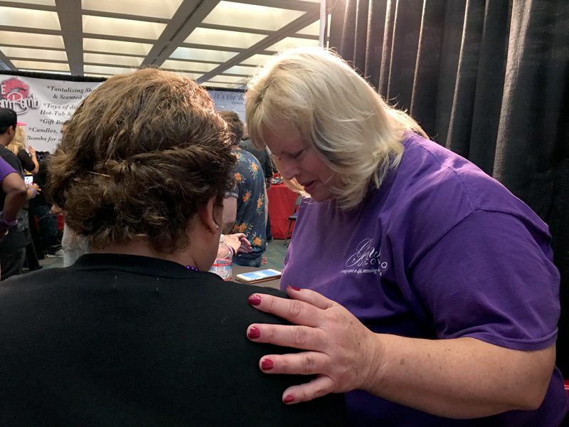 A volunteer prays with a visitor to The Salvation Army’s AdultCon booth. | Photo by Jackeline Luna