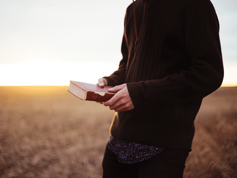 Person holding Bible outside