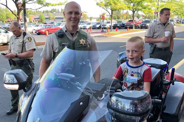 Child Sitting on Officer's Motorcycle with Smiling Cop