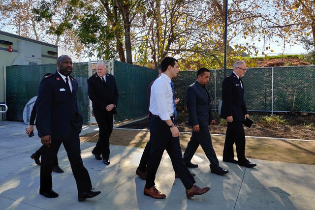 Mayor Pete Buttigieg walking with Salvation Army officers outside