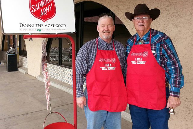 Two men with aprons next to red kettle