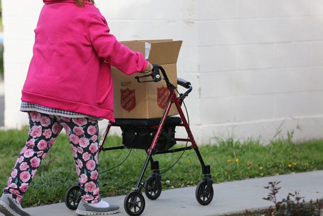 Woman walking with walker and box