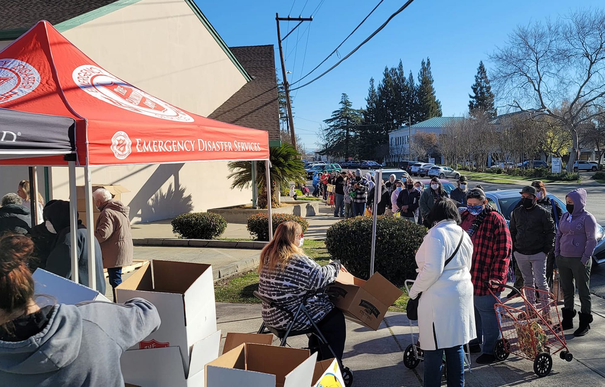 people wait in line for food boxes at the salvation army